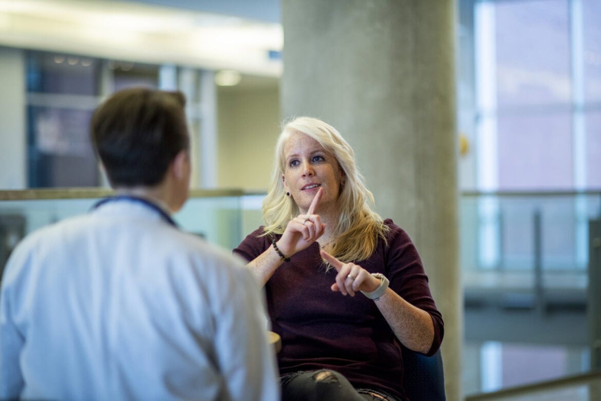 A deaf person is signing and catching up with a colleague.
