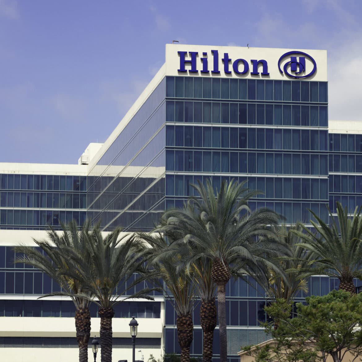 Exterior photo of Hilton Anaheim, with palm trees in front.
